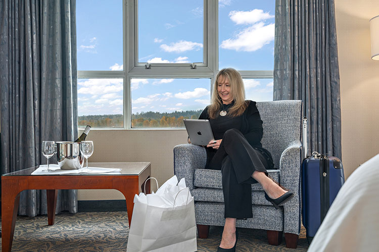 Person working on computer next to shopping bags and wine chilling with 2 glasses.