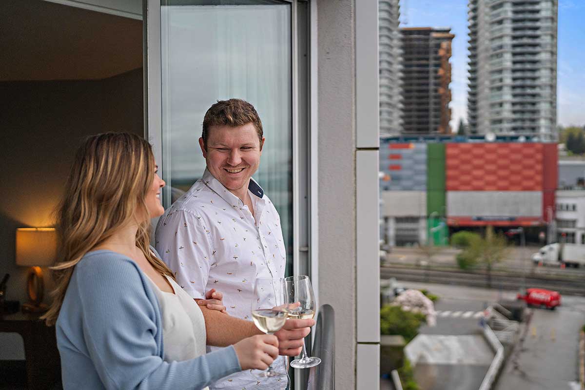 Couple toasting with with white wine on a hotel room balcony
