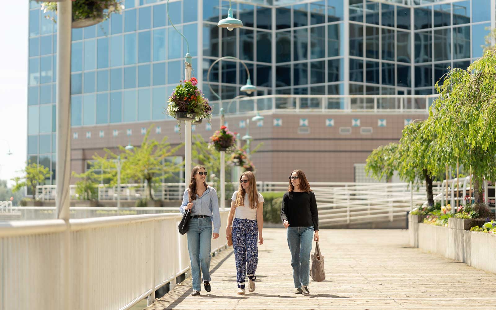 People strolling along the waterfront boardwalk in New Westminster, BC, surrounded by urban riverfront scenery ideal for a leisurely fall day.